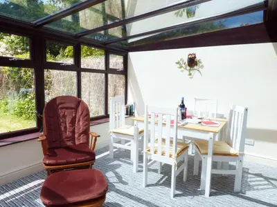 a dining room with a table and chairs and windows at 27 Swan Street in Boxford