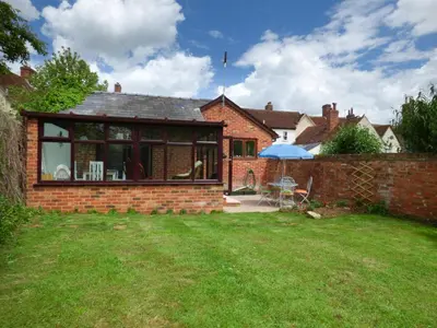 a brick house with a patio and an umbrella at 27 Swan Street in Boxford