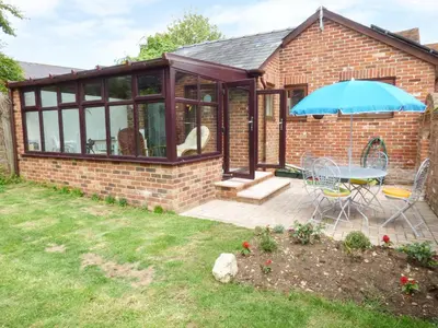 a brick house with a table and an umbrella at 27 Swan Street in Boxford