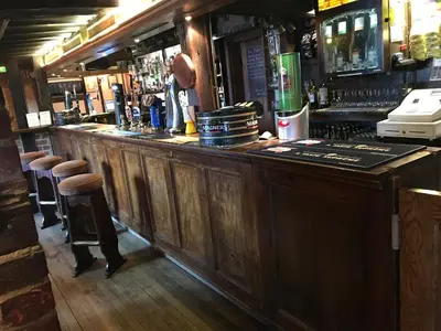 a large wooden bar with stools in a pub at The Black Bull Inn in Fyfield