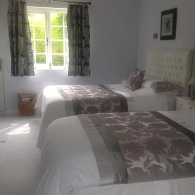 a bedroom with two beds and a window at The Coach House in Shepreth
