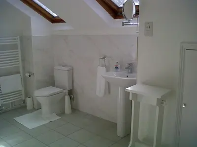 a white bathroom with a toilet and a sink at The Coach House in Shepreth