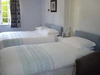 two beds in a room with white sheets at The Coach House in Shepreth