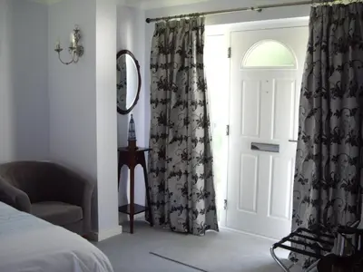 a bedroom with a bed and a chair and a window at The Coach House in Shepreth