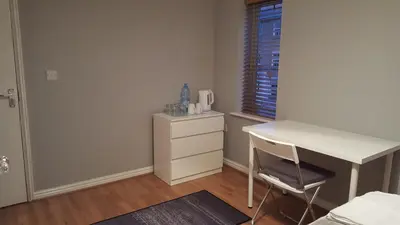 a bedroom with a desk and a dresser and a window at Haus Serviced Living in Braintree
