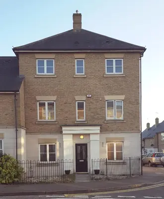 a large brick house with a black gate at Haus Serviced Living in Braintree