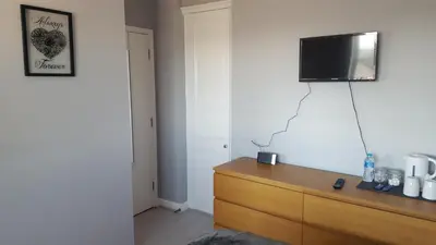 a room with a dresser with a television on the wall at Haus Serviced Living in Braintree