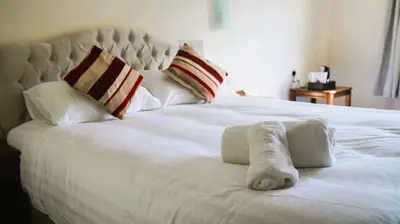 a white bed with a rolled up towel on it at The New Chichester Hotel in Wickford