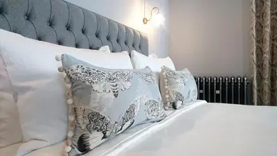a bed with white pillows and a blue headboard at The Mill, Long Melford in Long Melford