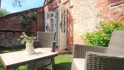 a table with chairs and a vase of flowers on it at The Mill, Long Melford in Long Melford