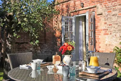 an outdoor table with a table cloth and flowers on it at The Mill, Long Melford in Long Melford