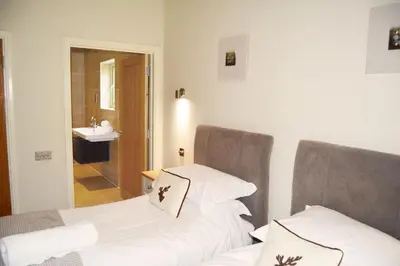 two beds in a room with a sink at Woodbell Lodge in Chappel