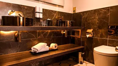 a bathroom with a toilet and towels on a shelf at Seven Hotel in Southend-on-Sea