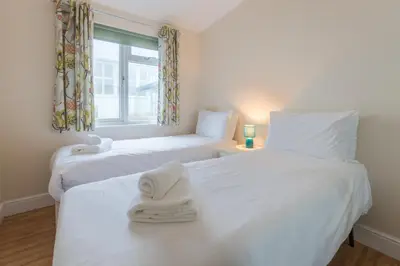 two white beds in a room with a window at Sole Bay View in Sizewell
