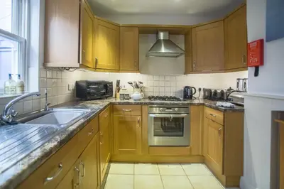 a kitchen with wooden cabinets and a sink at Pugwash in Aldeburgh