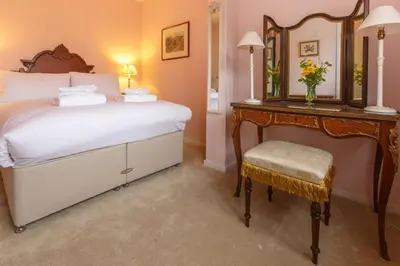 a bedroom with a bed and a mirror and a chair at Jasmine Cottage, Kelsale, sleeps 5 - Aldeburgh Coastal Cottages in Kelsale