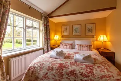 a bedroom with a large bed with two pillows at Jasmine Cottage, Kelsale, sleeps 5 - Aldeburgh Coastal Cottages in Kelsale