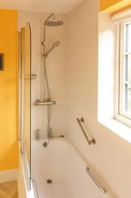 a bathroom with a bath tub with a shower at Jasmine Cottage, Kelsale, sleeps 5 - Aldeburgh Coastal Cottages in Kelsale