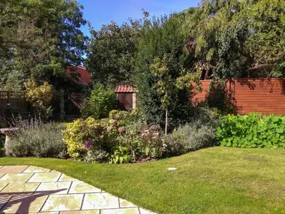 a garden with flowers and a brick fence at Jasmine Cottage, Kelsale, sleeps 5 - Aldeburgh Coastal Cottages in Kelsale