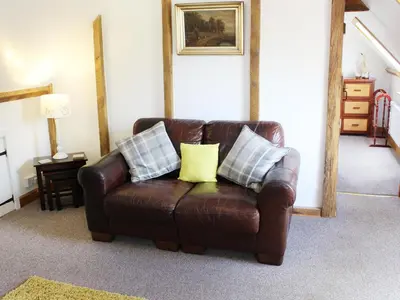 a brown leather couch with two pillows in a living room at The Hayloft in West Bradenham