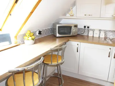 a kitchen with a counter with stools and a microwave at The Hayloft in West Bradenham