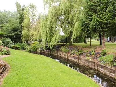 a river in a park with grass and trees at The Hayloft in West Bradenham
