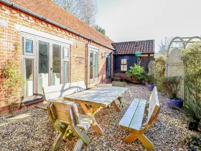 a patio with a wooden table and two chairs at Stable Cottage in West Bradenham