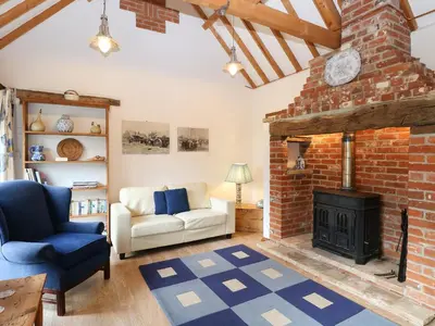 a living room with a brick fireplace and a couch at Stable Cottage in West Bradenham