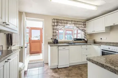 a kitchen with white cabinets and a window at Violet Cottage in Feltwell