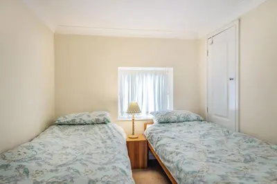a bedroom with two beds and a window at Violet Cottage in Feltwell
