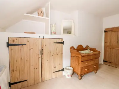 a room with a wooden wardrobe and a wooden dresser at Manor Farm Cottage in Swaffham
