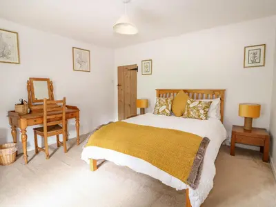 a bedroom with a bed and a table and a desk at Manor Farm Cottage in Swaffham