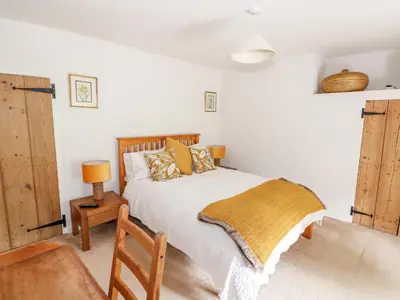 a bedroom with a bed with a wooden headboard at Manor Farm Cottage in Swaffham