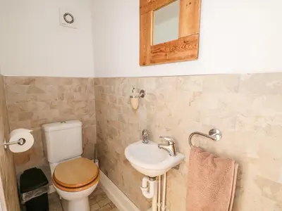 a bathroom with a toilet and a sink and a mirror at Manor Farm Cottage in Swaffham