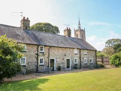 an old stone house with a tower on top of it at Manor Farm Cottage in Swaffham