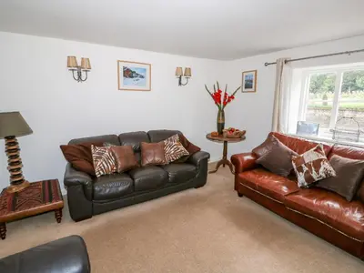 a living room with two leather couches and a window at Manor Farm Cottage in Swaffham