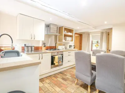 a kitchen with white cabinets and a table and chairs at The Hayloft in Ashill