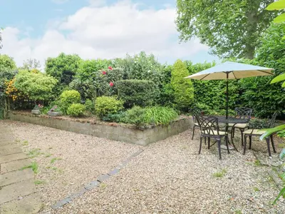 a table and chairs with an umbrella in a garden at The Hayloft in Ashill