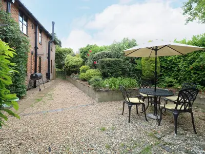 a table and chairs with an umbrella in a garden at The Hayloft in Ashill