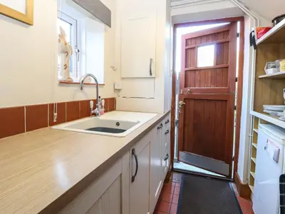 a kitchen with a sink and a wooden door at The Dairy in Ashill
