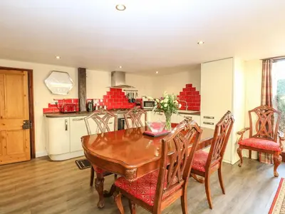a kitchen and dining room with a wooden table and chairs at The Barn in Ashill