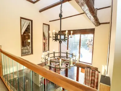 a dining room with a chandelier and a staircase at The Barn in Ashill