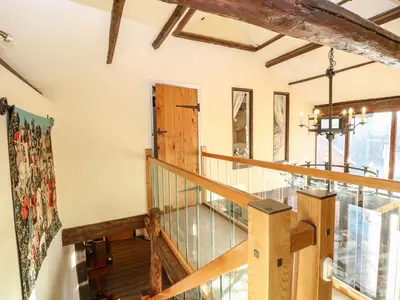 a wooden staircase in a house with a window at The Barn in Ashill