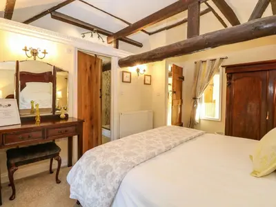 a bedroom with a bed and a vanity and a mirror at The Barn in Ashill