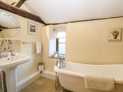 a bathroom with a bath tub and a sink at The Barn in Ashill