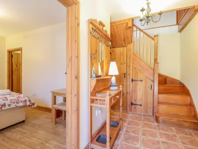 a bedroom with wooden walls and a staircase in a house at Hayloft Cottage in Little Glenham
