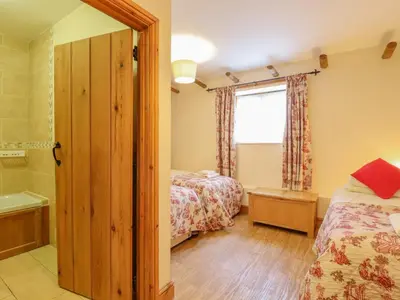 a bedroom with two beds and a tub and a window at Hayloft Cottage in Little Glenham