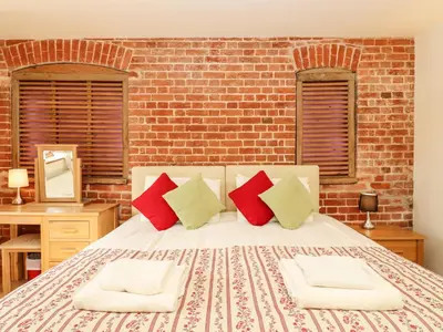 a bedroom with a bed with red and green pillows at Poppy Cottage in Little Glenham