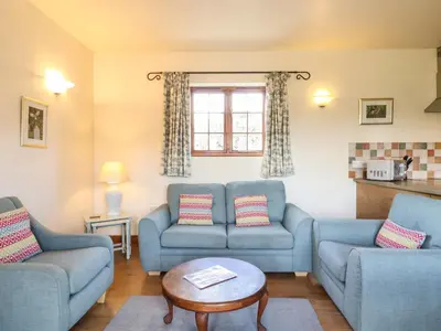 a living room with two blue couches and a table at Barn Owl Cottage in Little Glenham