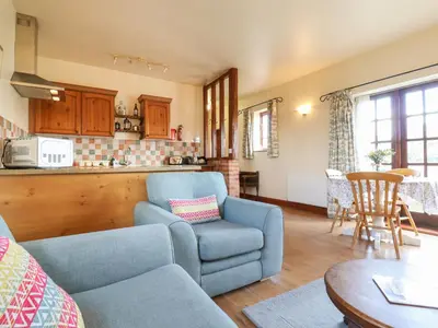 a living room with a couch and a chair and a table at Barn Owl Cottage in Little Glenham